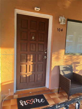 Front view of a house entrance with a wooden door and a doormat.