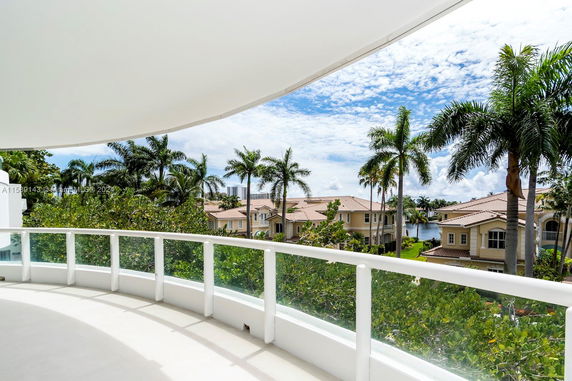 Panoramic view from a balcony overlooking houses and palm trees.