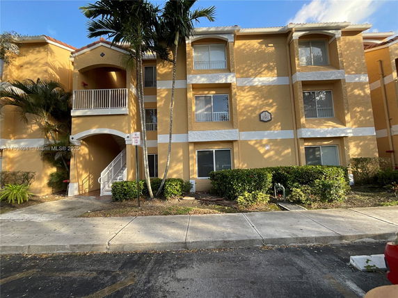 Front view of a three-story building with balconies and a staircase.