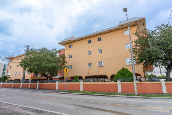 Front view of a multi-story residential building with arched ground floor.