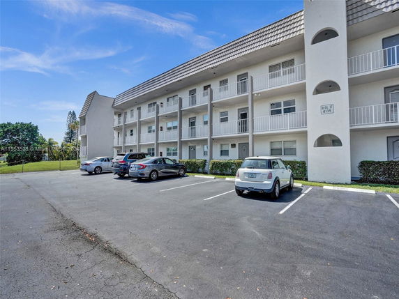 Outdoor parking area in front of a multi-story residential building.