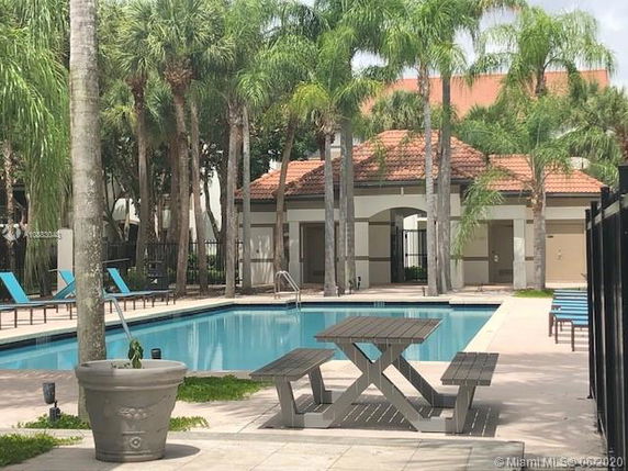 Outdoor swimming pool area with surrounding palm trees and seating benches.