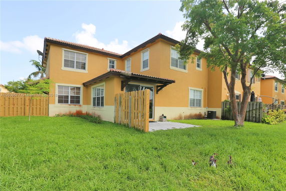 Side view of a two-story house with yellow walls and a brown roof