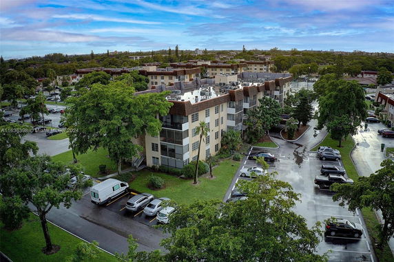 Aerial view of multiple apartment buildings surrounded by trees and parking lots.