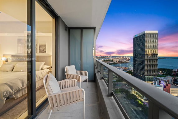 Balcony view overlooking cityscape and water with a high-rise building in the foreground.