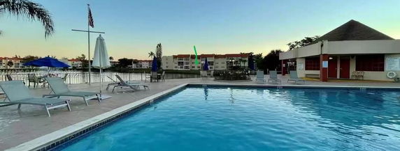 Outdoor swimming pool area with lounge chairs and umbrellas.