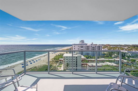 Panoramic view from a balcony showing the ocean and buildings.