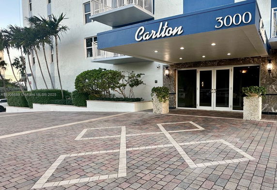 Front view of a building entrance with a canopy and tiled pathway.