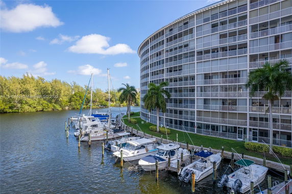 View of a multi-story building with balconies alongside a waterway with docked boats.