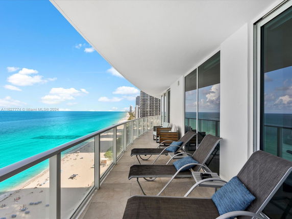 Balcony view from a high-rise building overlooking a beach and ocean.
