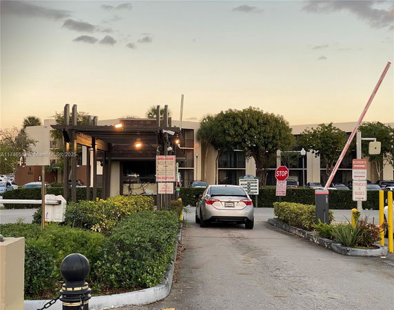 Outdoor parking area with a car stopped at a barrier gate.