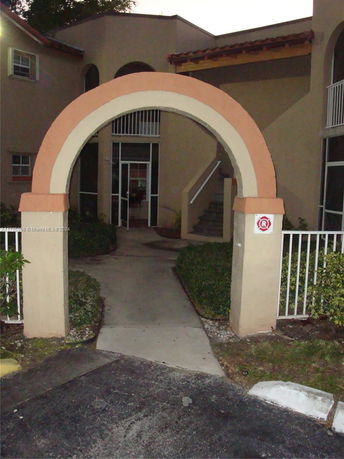 Front view of a building with an archway entrance and stairs.