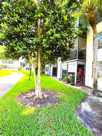 View of an apartment building with trees and landscaped grass area.