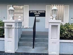 Front view of a building entrance with steps and white columns topped with lanterns.