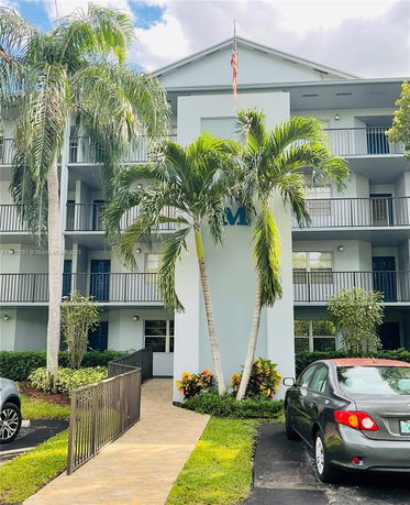 Front view of a multi-story building with balconies and a walkway.