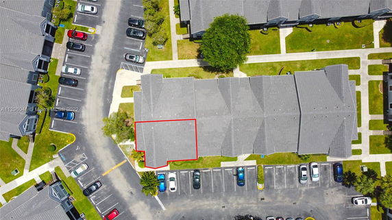 Aerial view of a building complex with adjacent parking lots filled with cars.