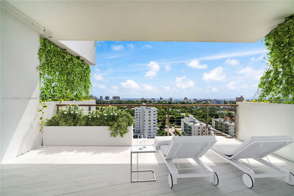 Panoramic balcony view overlooking a cityscape with buildings and greenery.