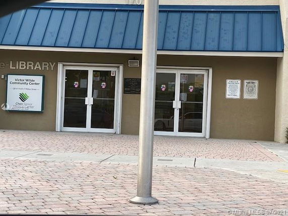 Front view of a building with a blue roof and double glass doors.