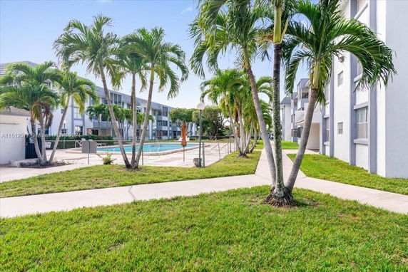 Outdoor view of a swimming pool surrounded by palm trees and multi-story residential buildings.