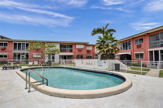 Outdoor swimming pool area in front of a multi-story building.