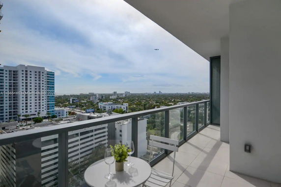 View from a balcony overlooking a cityscape with tall buildings and a distant horizon.