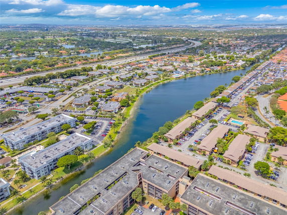 Aerial view showcasing residential buildings, a lake, and roads.