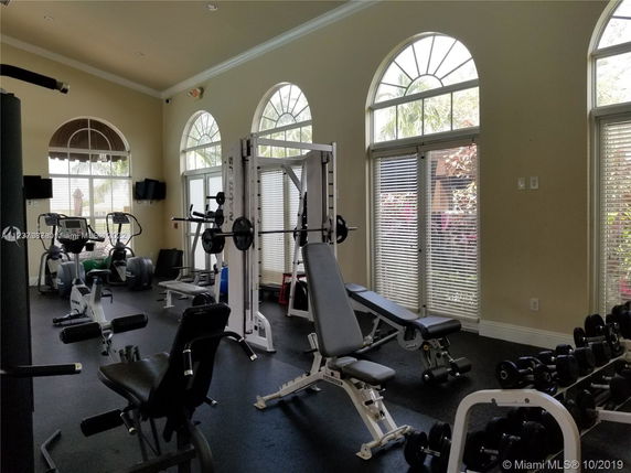 Interior view of a gym with exercise equipment and large windows.