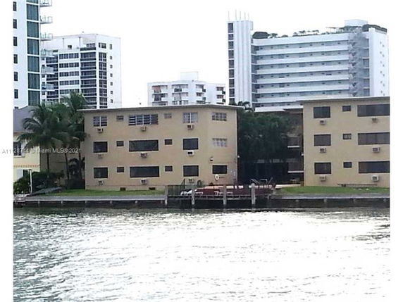 View of a waterfront apartment building with multiple stories seen from across the water.
