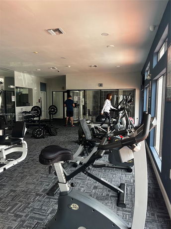Interior view of a gym with exercise equipment including stationary bikes and weights.