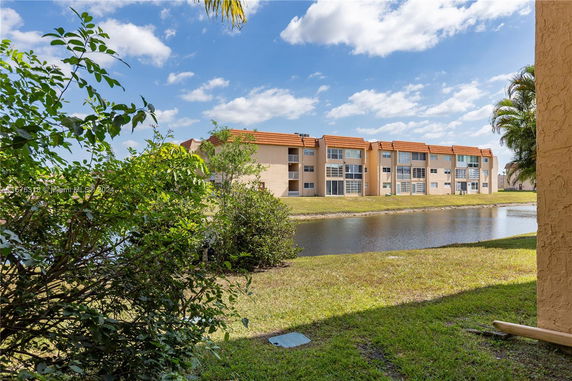 View of residential buildings with an orange roof near a body of water.