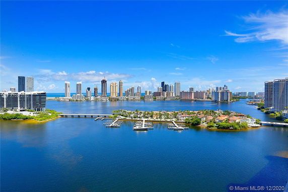 Panoramic view of a coastal cityscape with tall buildings and waterbodies.