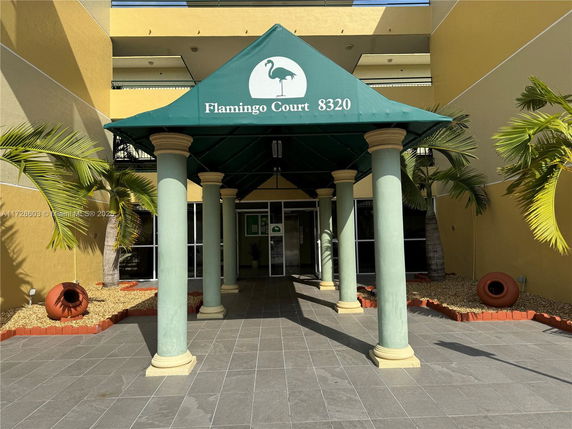 Front view of a building with a green canopy entrance supported by columns.