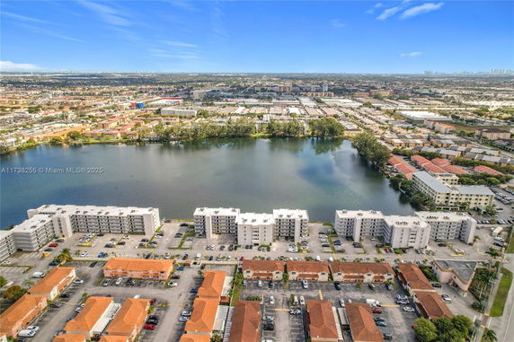 Aerial view of residential buildings near a body of water with a cityscape in the background.