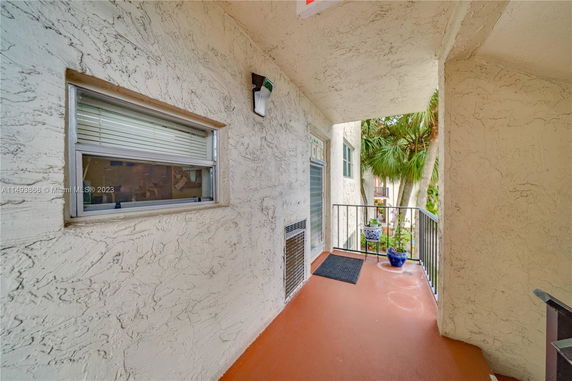 Exterior view of a building corridor with textured walls and a small window.