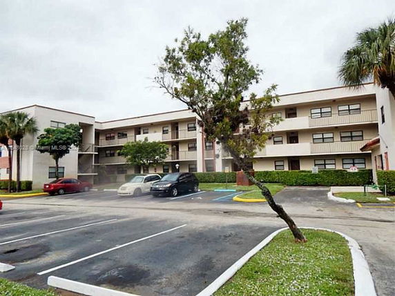 Front view of a multi-story building with adjacent parking area.