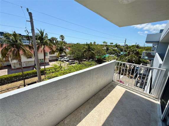 Balcony view with surrounding buildings and palm trees.