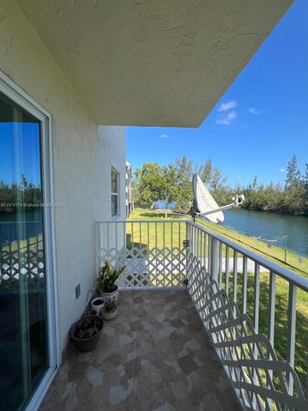 Outdoor view from a balcony overlooking a grassy area and a water body.