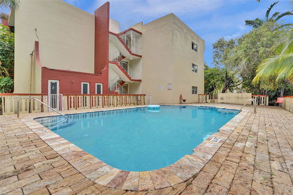 Outdoor swimming pool beside a building with multiple exterior staircases.