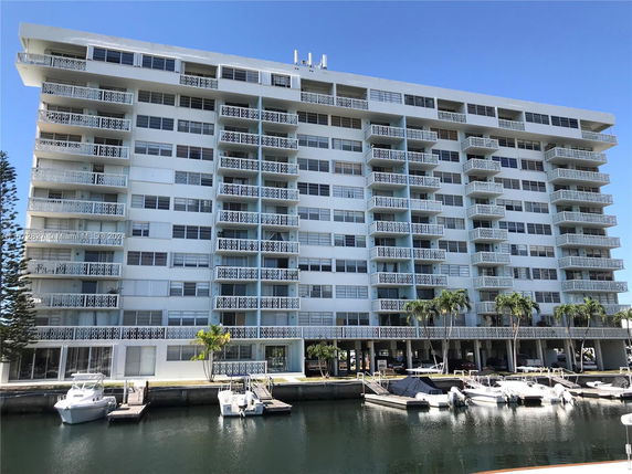 Front view of a multi-story apartment building with balconies and waterfront access.