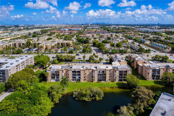 Aerial view of a residential area with multiple apartment buildings near a body of water and city skyline in the distance.