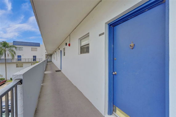Exterior hallway of a residential building with blue doors.