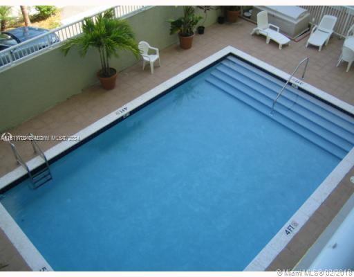 Outdoor swimming pool with lounge chairs and potted plants around the perimeter.