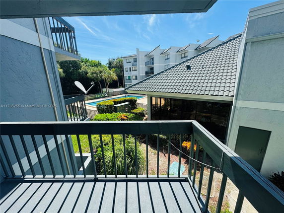 View from a balcony overlooking a swimming pool and surrounding buildings.