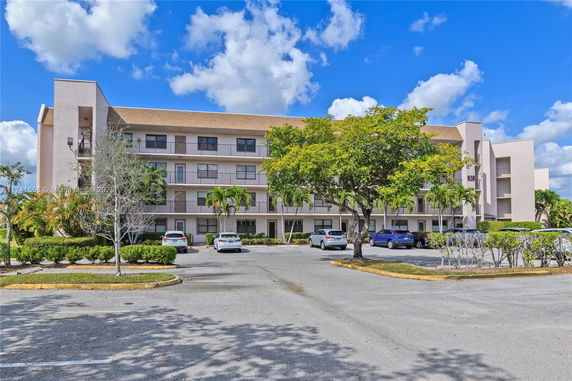 Front view of a multi-story apartment building with parking area.