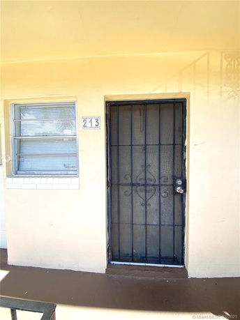 Front view of a building entrance with a barred door and adjacent window.