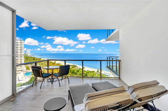 View from a balcony overlooking the ocean and nearby buildings.