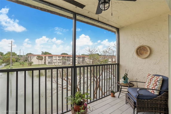 View from a balcony overlooking a pond and adjacent apartment buildings.