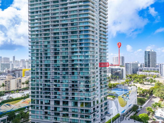 View of a tall residential apartment building with multiple balconies.