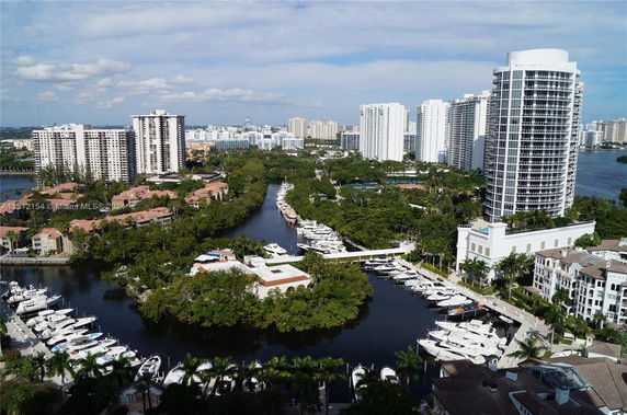 Panoramic view of a waterfront area with high-rise buildings and docked boats.