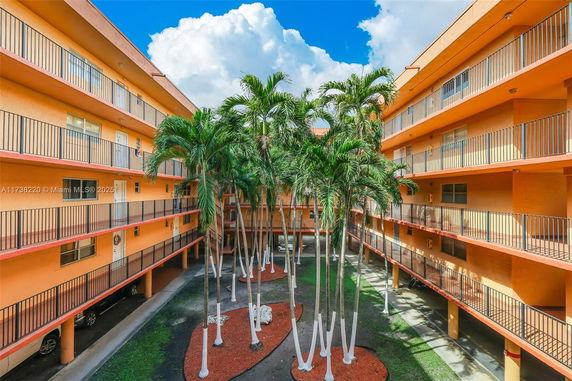 View of a multi-story apartment building's courtyard with palm trees planted in the center.